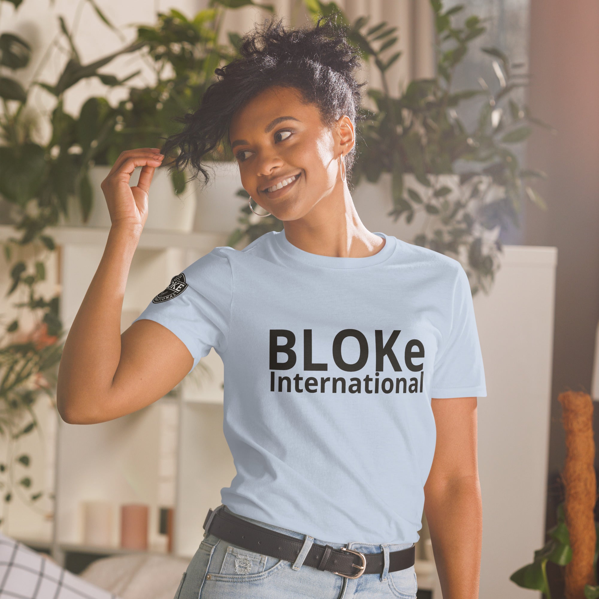 Smiling woman in light blue Bloke International T-shirt in cozy home setting