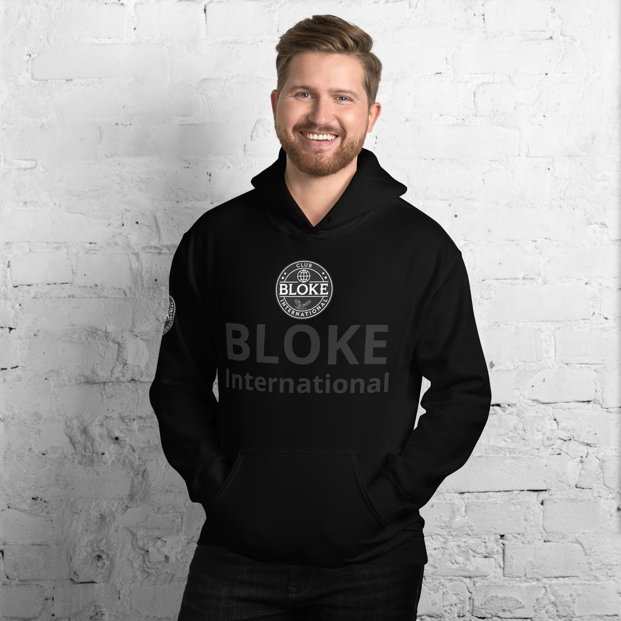 Smiling man in Club Bloke Christian hoodie against a brick wall